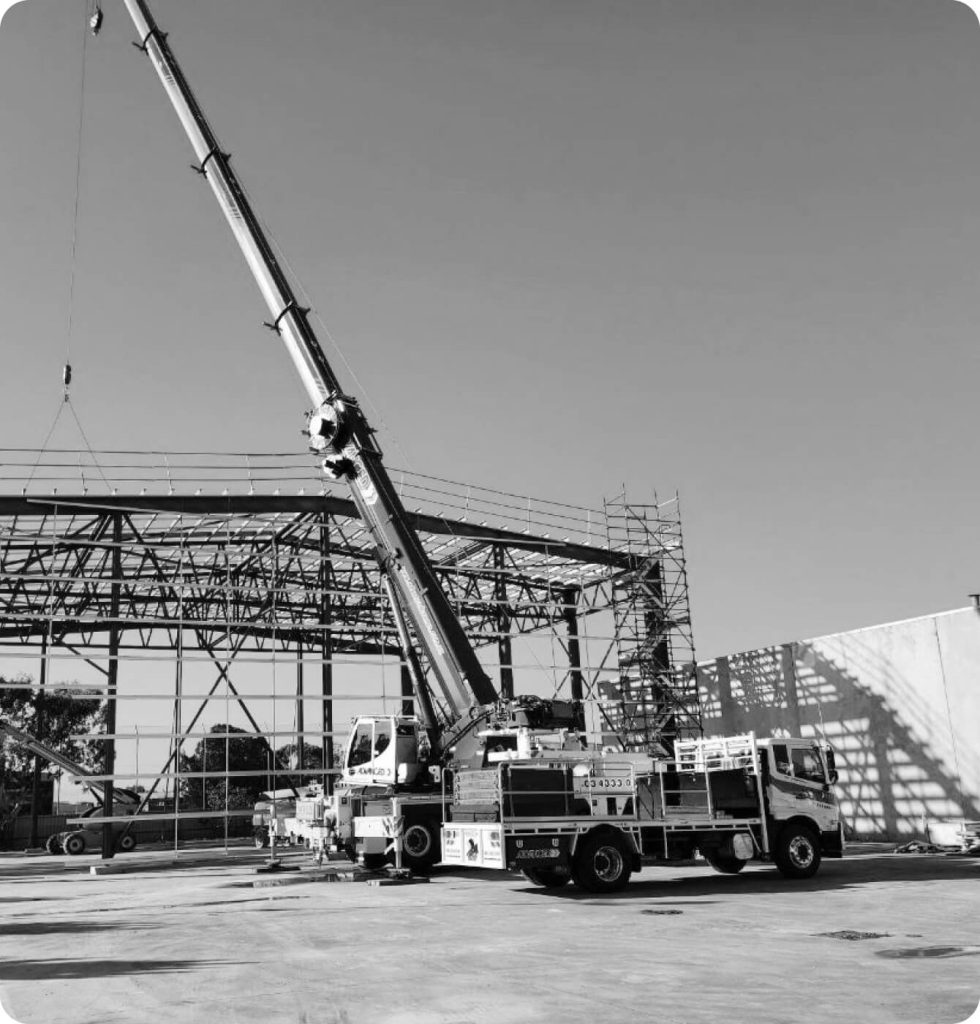 A black and white photo of a crane lifting a large structure.
